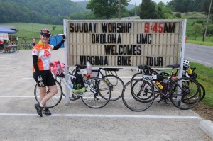 Bike Virginia woman rider stands with bikes in front of sign with at rest stop